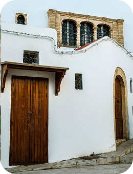 White building with two wooden doors and decorative stone-framed windows above.